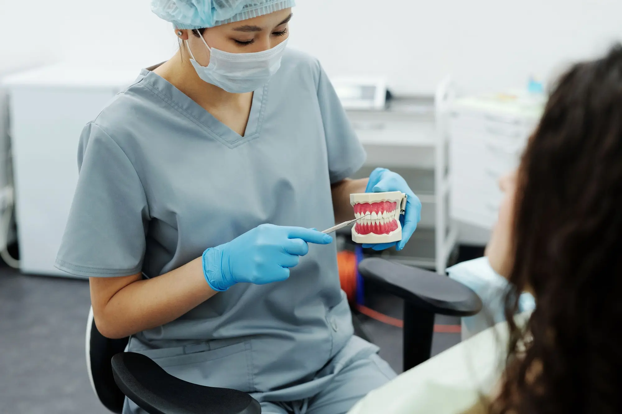 A dentist pointing at images on a monitor while talking with a seated patient