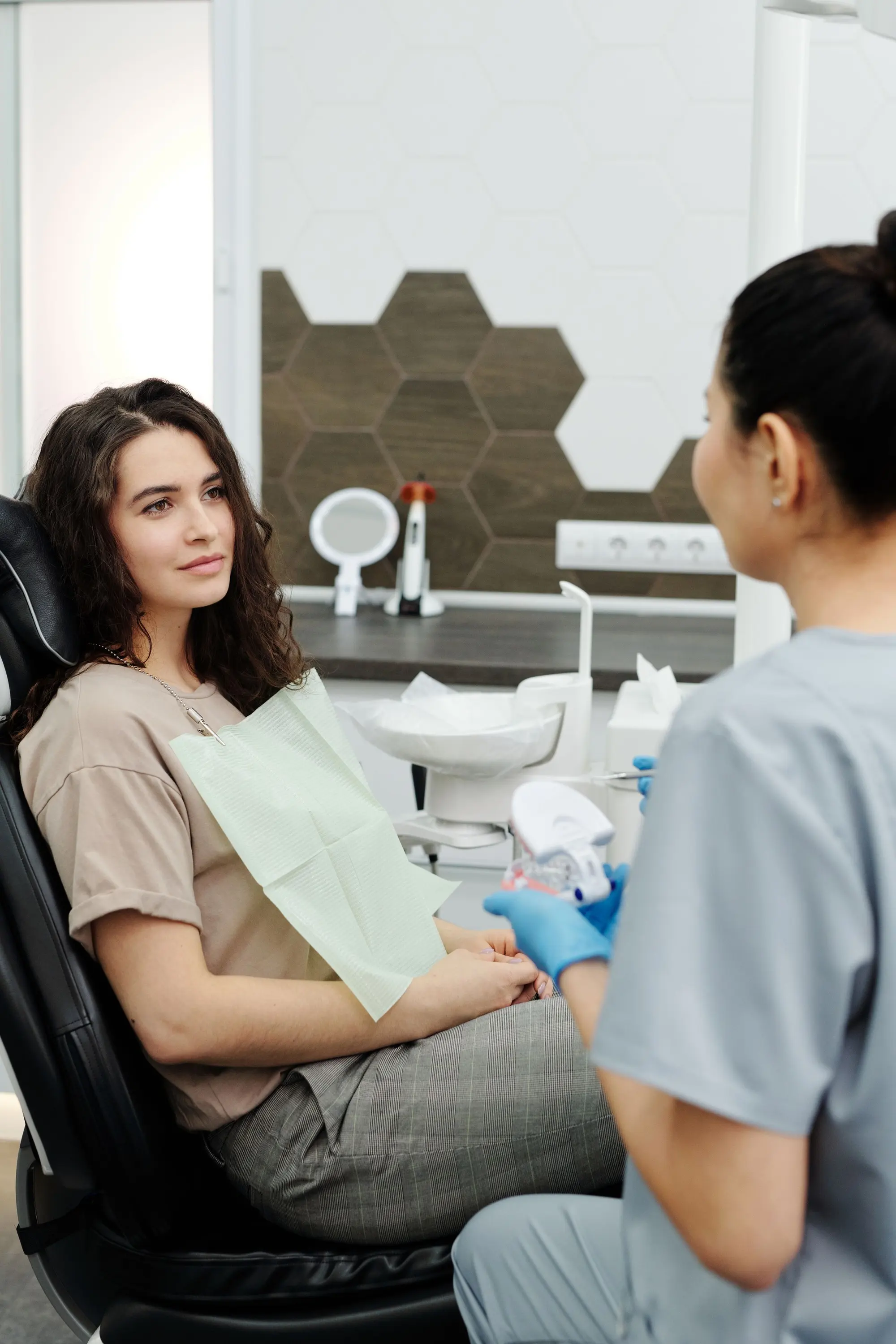 A patient in a treatment chair listening while a dentist explains her exam