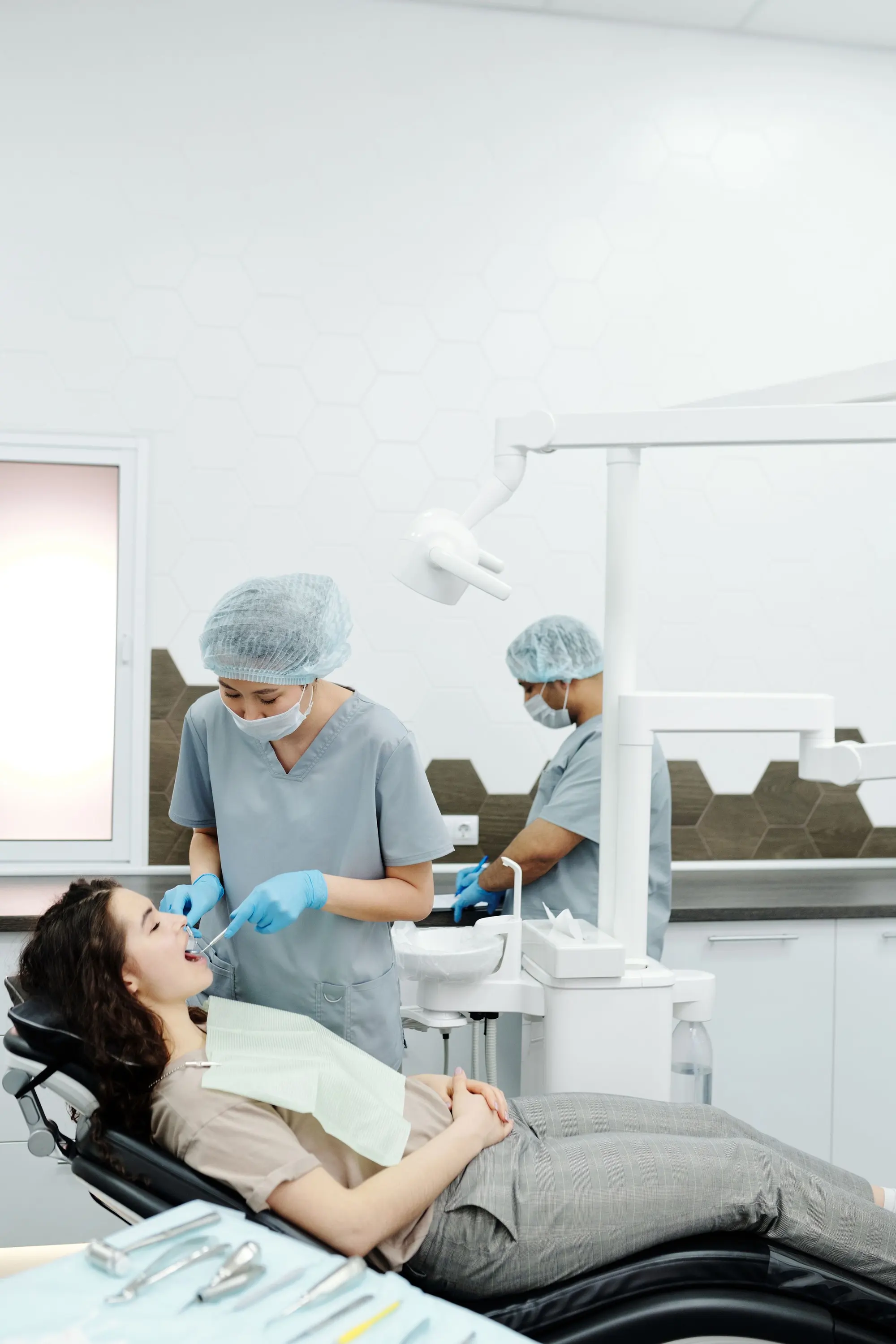 A patient reclined in a treatment chair while two members of the team prepare for an exam